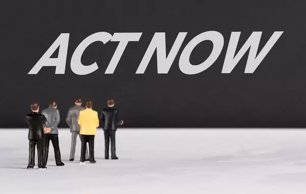 People standing in front of Act Now text