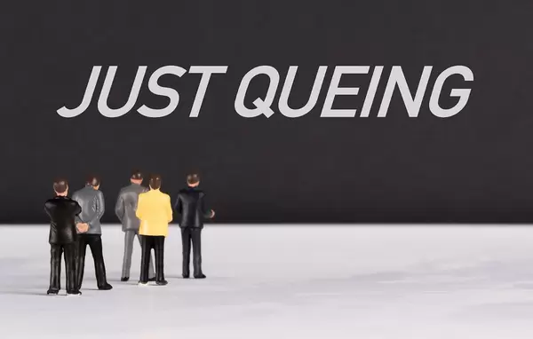 People standing in front of Just Queing text