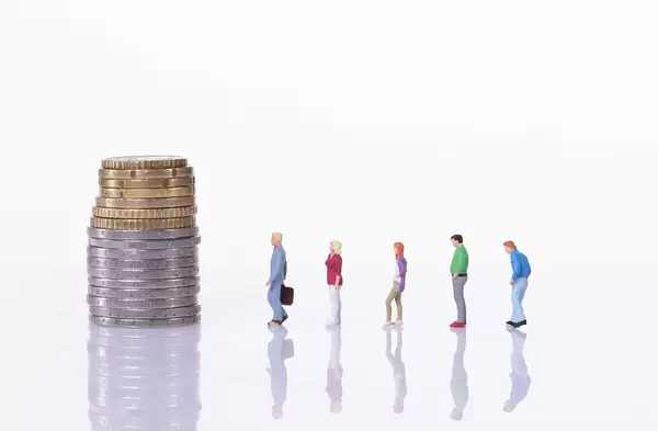 People standing in line in front of coin stack on white background
