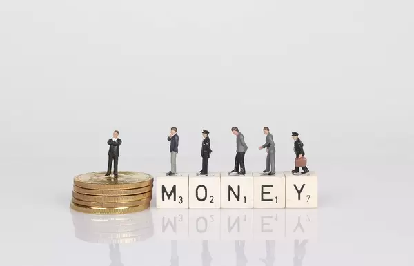 People standing on wooden cubes with money text