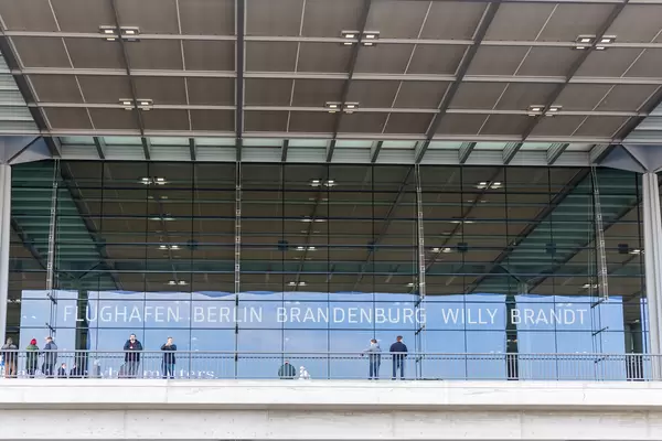 People with face mask and the glass front of Terminal 1 of Berlin Brandenburg Willy Brandt airport