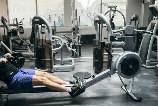 Person exercising on a rowing machine in an empty gym
