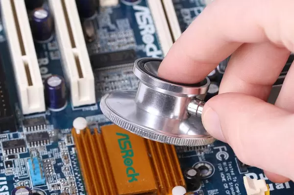 Person hält ein Stethoskop über eine Hauptplatine eines Computers Nahaufnahme
