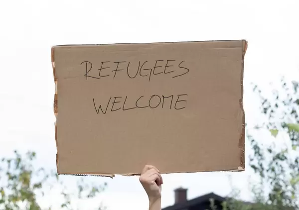 Person hält Karton mit der Nachricht "Refugees Welcome"