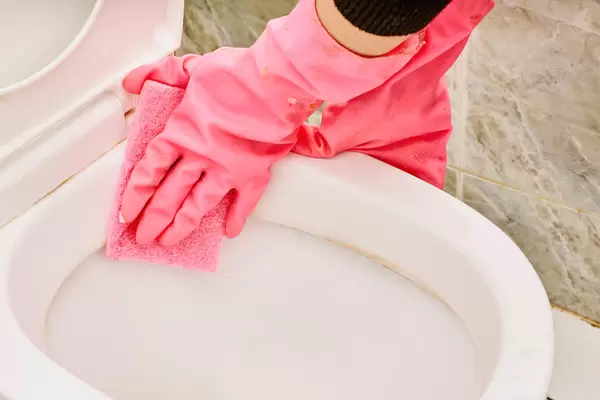 Person hand cleaning toilet using sponge