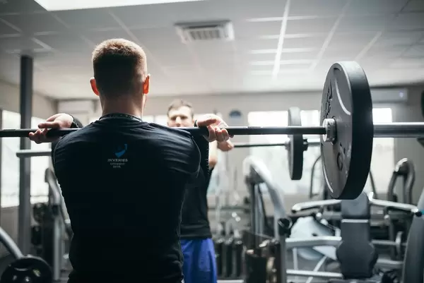 Person in front of a mirror in a gym in starting postition of a military press