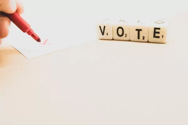 Person marking a vote with dice reading VOTE