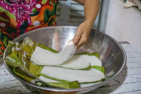 Person placing Vietnamese Rice Vermicelli Banh Hoi on Banana Leaves in a Bowl at a Noodle Factory in the Mekong Delta in Vietnam