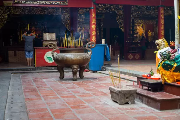 Person praying with burning Incense Sticks in front of an Altar inside Quan Am Pagoda in District 5 in Saigon, Vietnam