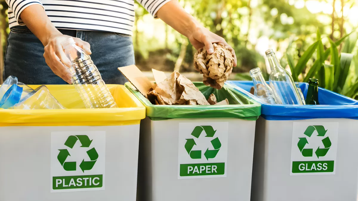 Person sortiert Müll in Recyclingbehälter für Plastik Papier Glas