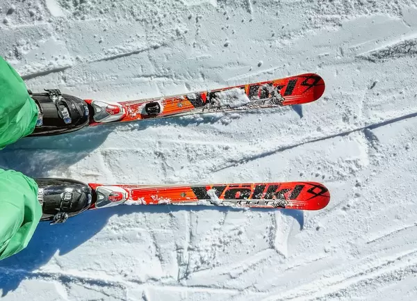 Person steht auf orangem Paar Ski auf Schnee