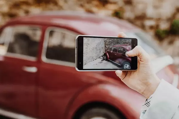 Person taking a Photo of Vintage Car with Smartphone