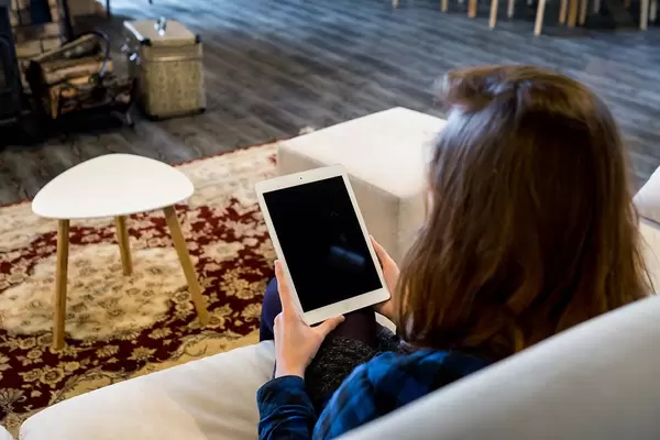 Person using an iPad while sitting on a Sofa in Co-working Space