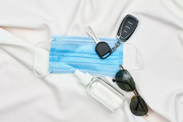 Personal hygiene accessories and car keys on white fabric background