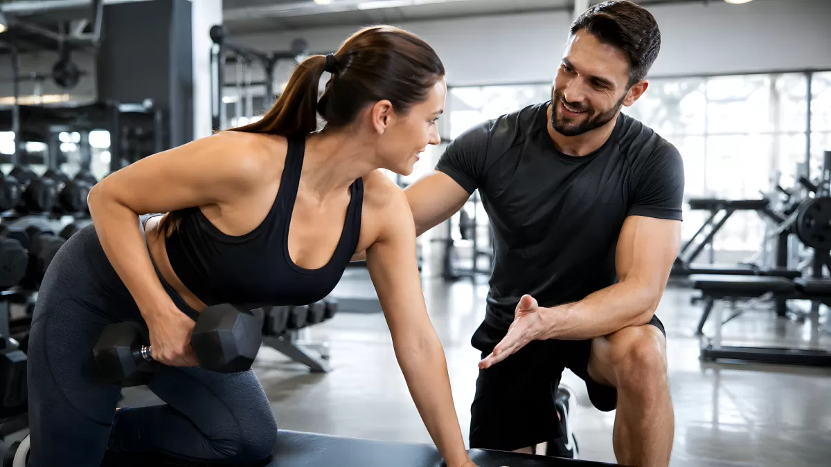 Personal Trainer betreut Frau beim Kurzhanteltraining