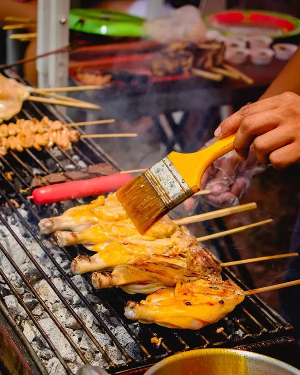 Person's hand brushing oil on a chicken barbecue (Flip 2019)