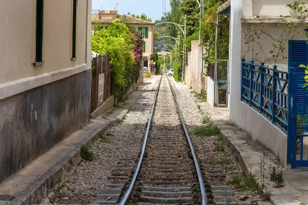 Perspective with rail tracks between houses with blooming gardens in Sóller on Majorca
