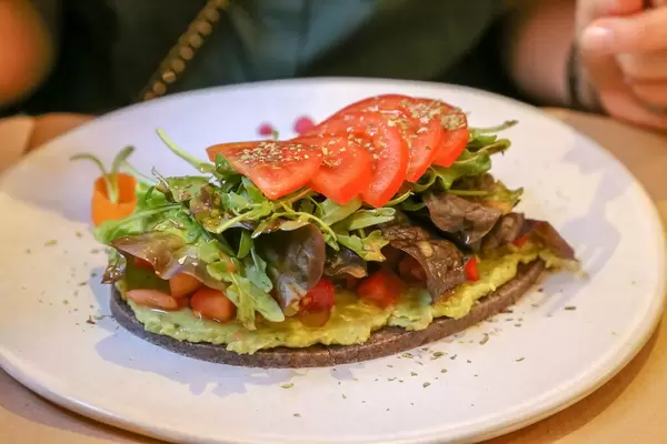Petit Pa mit Tomaten & Avocado, Brot aus Sonnenblumen & Leinsamen, grünem Salat, Olivenöl und Oregano im Petit Brot in Barcelona, Spanien