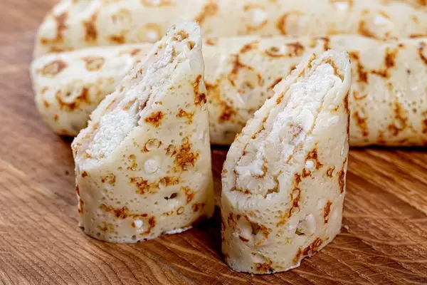Pfannkuchen gefüllt mit süßem Hüttenkäse auf einem Holztisch