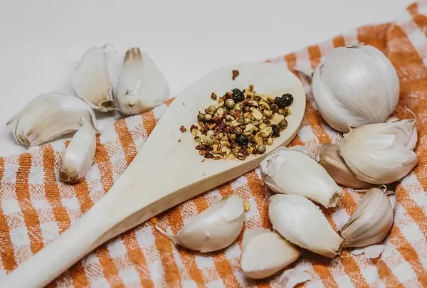 Pfeffer im Holzlöffel und Knoblauchzehen