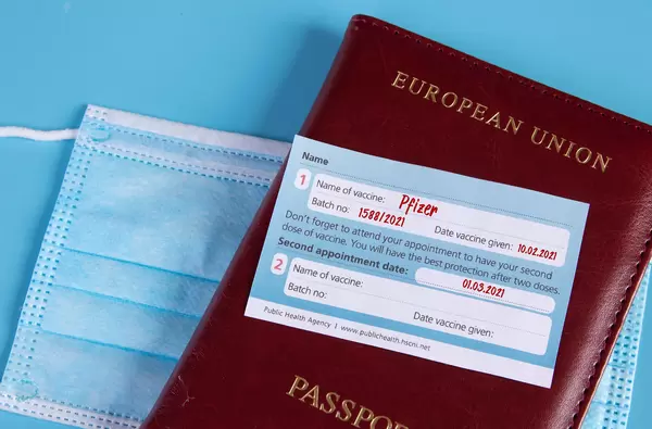 Pfizer Covid-19 vaccination certificate with passport and medical face mask