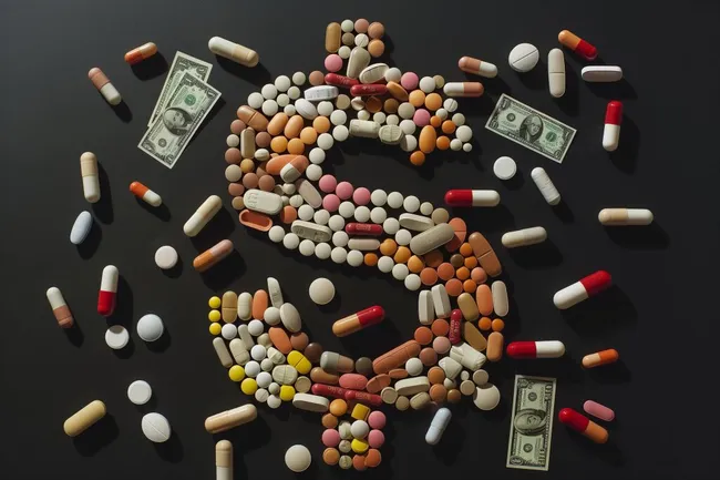 Pharmazeutische Pillen und Dollarscheine vor dunklem Hintergrund