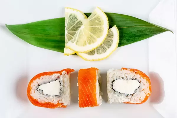 Philadelphia sushi on a white plate with lemon slices, top view