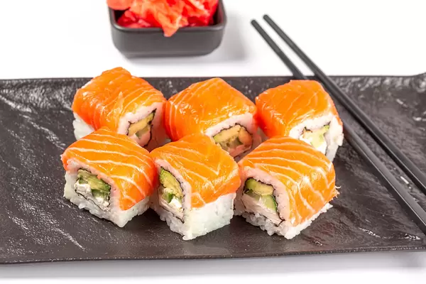 Philadelphia sushi with salmon on a black tray with chopsticks