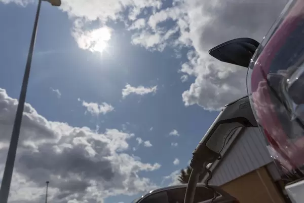 Phoenix Contact Typ 2 Stecker zum Aufladen von Sonnenenergie für Tesla Elektroautos Model 3 auf einem Aldi-Süd Parkplatz, mit Wolken vor der Sonne