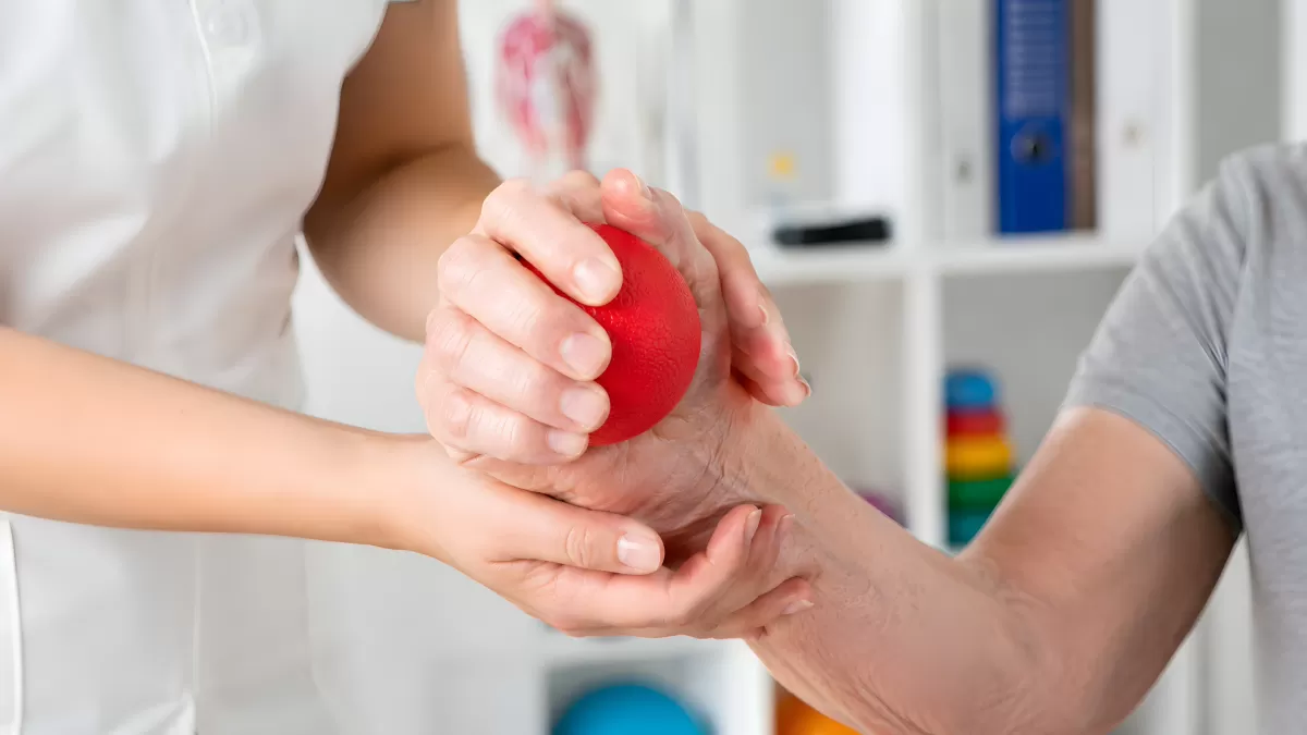 Physiotherapeutin unterstützt Patient bei Handübung