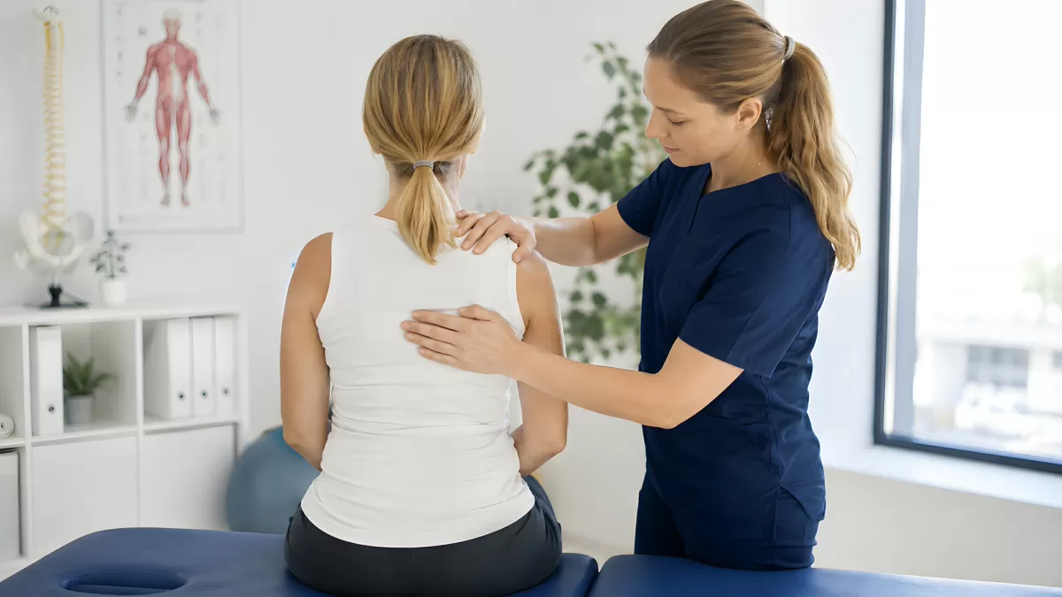 Physiotherapeutin untersucht Rücken einer Patientin