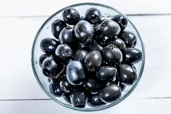 Pickled olives in glass bowl on white background, top view  Flip 2019