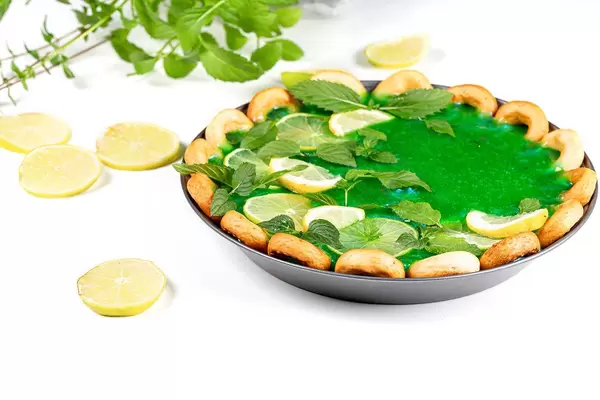 Pie with green mirror glaze, fresh mint leaves and citrus