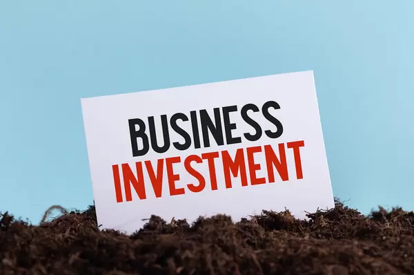 Piece of paper with Business Investment text on a dirt
