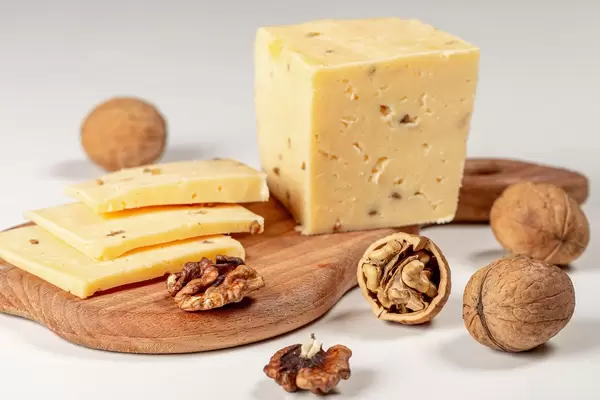 Pieces of cheese with walnuts on wooden kitchen Board (Flip 2020)