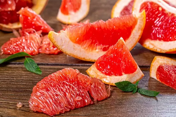 Pieces of fresh grapefruit on a brown wooden background (Flip 2019)