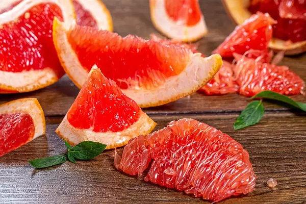Pieces of fresh grapefruit on a brown wooden background