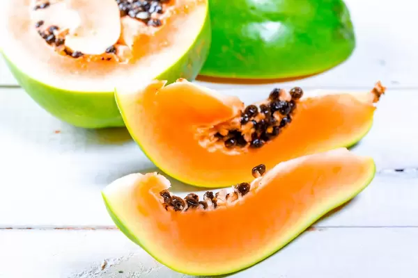 Pieces of fresh ripe papaya on white wooden background