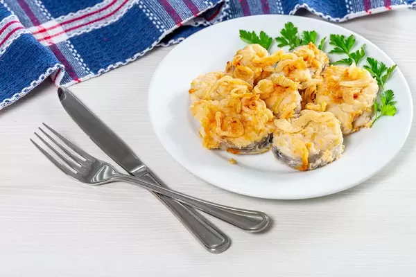 Pieces of fried fish with fried onions and parsley on a white plate (Flip 2019)