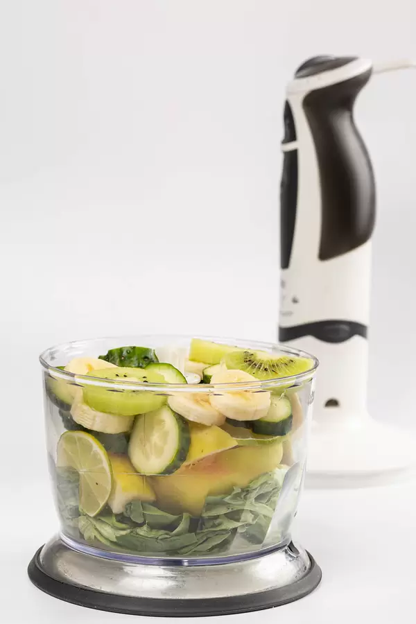 Pieces of fruits, vegetables and herbs in a blender