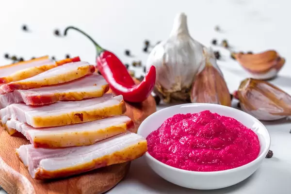 Pieces of smoked bacon on the kitchen Board with horseradish sauce, garlic, chili and pepper mixture