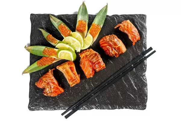 Pieces of smoked salmon with sliced lime and red caviar, top view