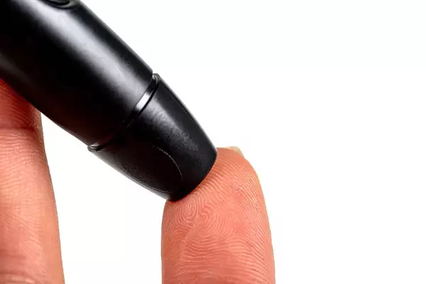 Piercing a finger, close up. Person's hand checking blood sugar level with glucometer