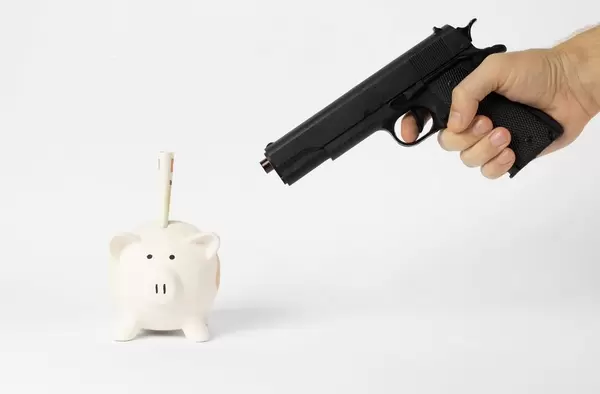 Piggy bank and hand with gun