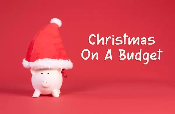 Piggy bank with Christmas hat and Christmas on a budget text on red background
