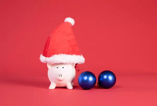 Piggy bank with Christmas hat and ornaments on red background