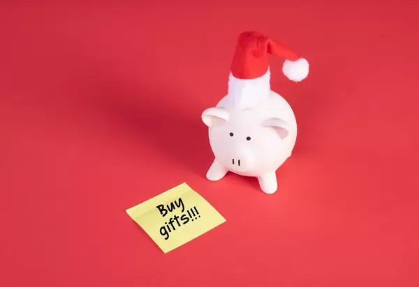 Piggy bank with Christmas hat and sticky note with Buy Gifts text