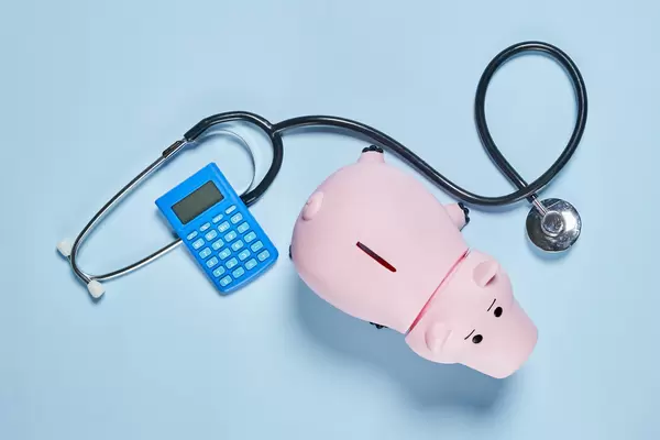 Piggy bank with stethoscope and calculator on blue background