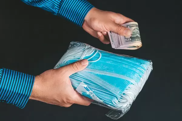 Pile of anti virus surgical face masks and money in man's hands
