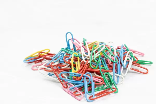 Pile of colorful Paper Clips above white background with copy space